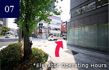 Using the elevator: Exit once you are above ground and go straight. Head toward the intersection on the right. Using the stairs: Keep going straight ahead.